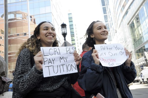 Mackenzie Thomas y Vivi Bonomie sostienen carteles mientras la actriz Lori Loughlin enfrenta cargos por presuntamente conspirar para cometer fraude postal y otros cargos en el escándalo de admisión a la universidad de sus dos hijas.