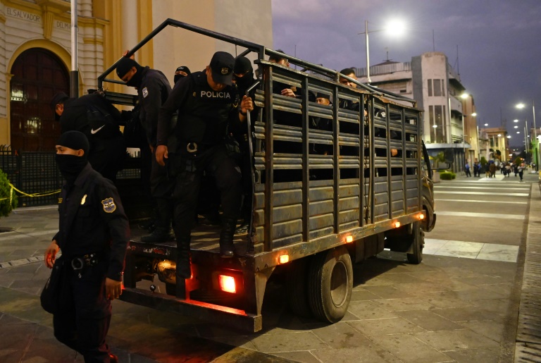 Un grupo de policías baja de un vehículo en una calle del centro histórico de San Salvador para aplicar la orden gubernamental de cuarentena domiciliaria (AFP)